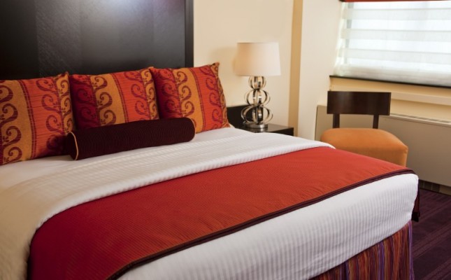 A bed with red and orange pillows and a white comforter