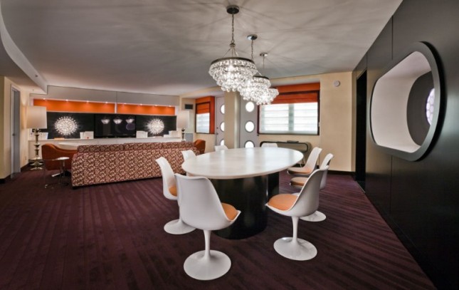 A hotel lobby with a round table and chairs, a counter, and a chandelier.