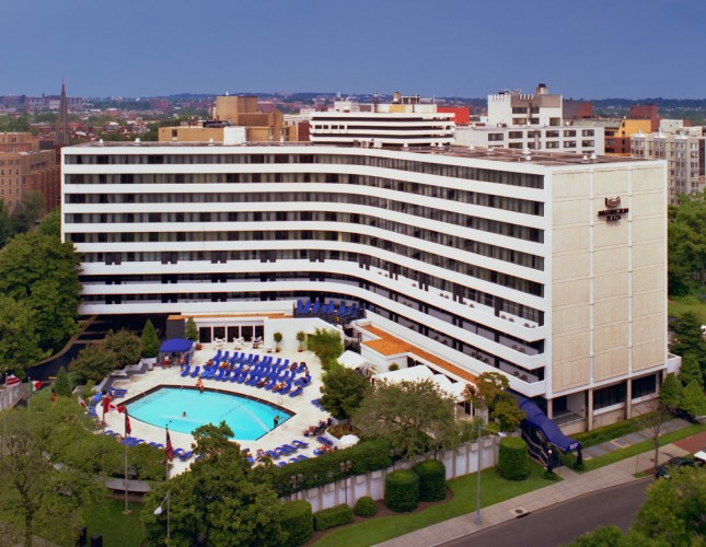 A large white hotel building with a pool and city view