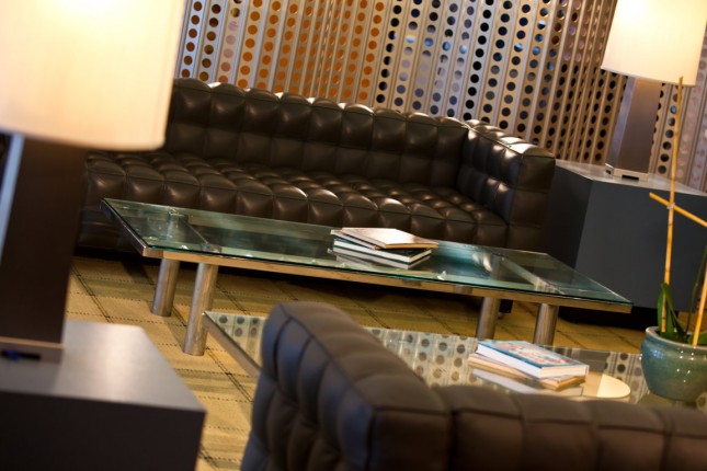 A lobby lounge with a leather sofa, glass coffee table, and lamps.