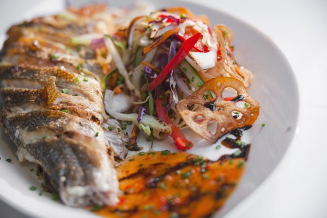 a plated dish with grilled fish and vegetables
